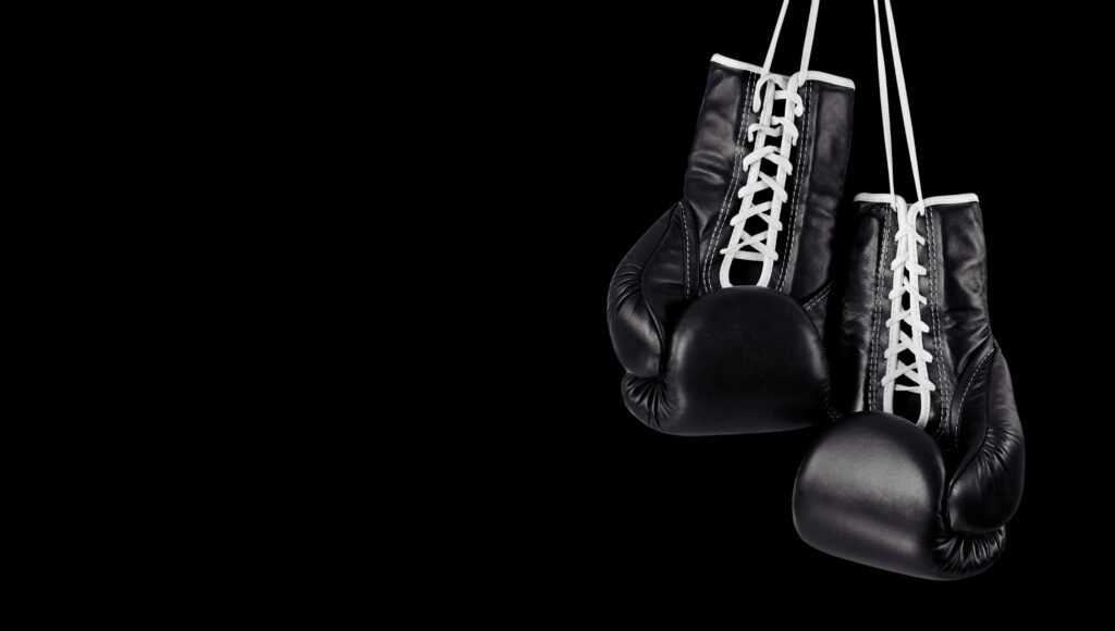 Guantes de boxeo negros colgando en un fondo negro, academia de boxeo en Calpe