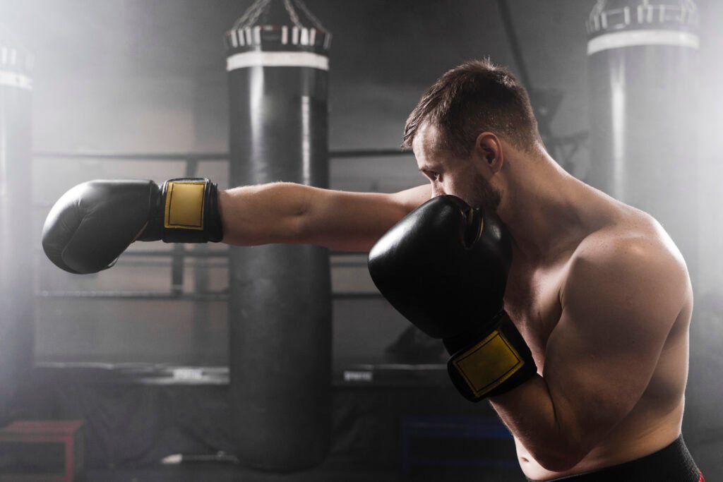 boxeador lanzando un puño con guantes de boxeo negros. Errores comunes al empezar a entrenar boxeo