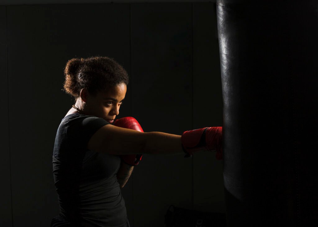 Mujer joven boxeando un saco de boxeo en Ilian Strike Academy, academia de boxeo