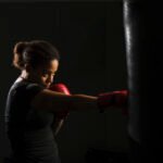 Mujer joven boxeando un saco de boxeo en Ilian Strike Academy, academia de boxeo